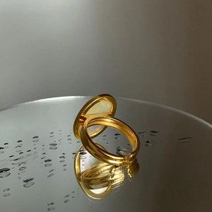 Detail view of gold open ring with oval shell inlay on reflective mirror surface
