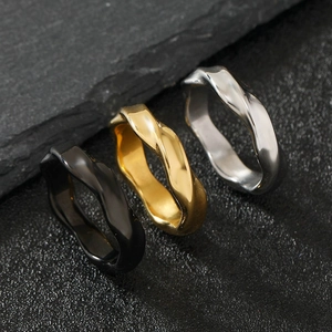 Polished titanium steel wave rings in black gold and silver on stone background