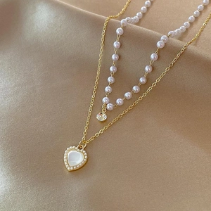 Close-up of double-layer necklace with white pearls and a golden heart pendant