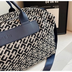 Gros plan sur le motif jacquard et le patch en cuir d'un sac de voyage bleu.
