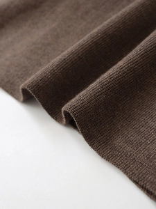 Makroaufnahme von dunkelkaffeebraunem Strickstoff zeigt hochwertige Wollmischung und Webung