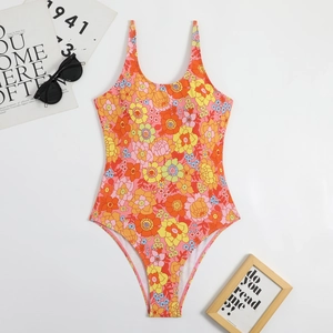 Flat lay of vintage floral one-piece swimsuit with sunglasses and summer props