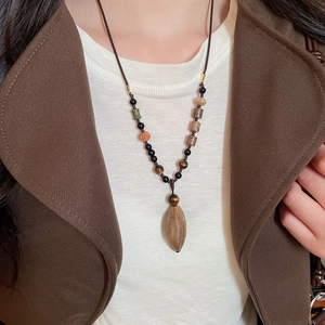 Detailed close-up of retro ethnic necklace with natural wood beads and botanical pendant