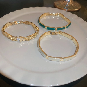 Detail view of gold-plated bracelets with cat eye stone, zircon and enamel inlay details