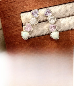 Macro detail of silver titanium steel cartilage studs with four colorful heart zircons