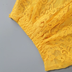 Dettaglio del tessuto in pizzo giallo brillante con intricati motivi floreali traforati