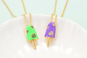 Macro detail of ice cream pendant with heart zircon and HAPPY engraving on gold metal
