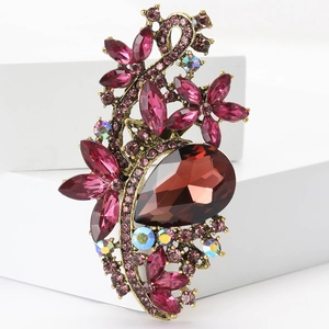 Detailed view of vintage gold-tone flower brooch with dark red crystals on white stand