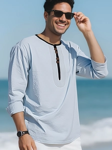 Detail of light blue linen-style shirt with black trim and buttons on the beach