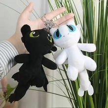 Close-up of plush Toothless and Light Fury keychains with metal clips in a garden