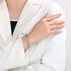 Close-up of a silver-toned hollow chain bangle on a wrist with polished metallic finish