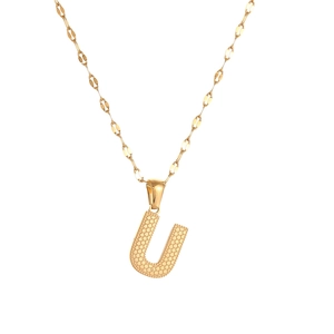 Detailed view of gold letter U pendant with embossed dot texture on a metal chain