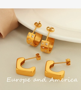 Detail of 18k gold plated stainless steel C-shape earrings with star patterns and stones