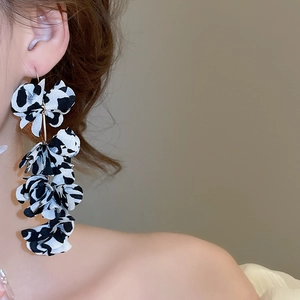 Detailed view of long fabric flower tassel earrings with leopard print on a female model