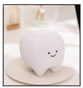 Detailed view of plush tooth toy with a smiling face on a textured white display stand