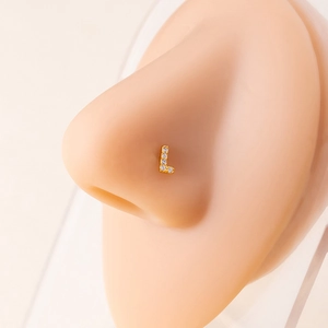 Detailed view of a gold L-shaped nose stud with clear zircon on a silicone model