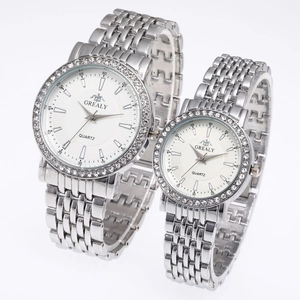 Gros plan sur les montres couple en argent avec lunette en strass et cadran blanc