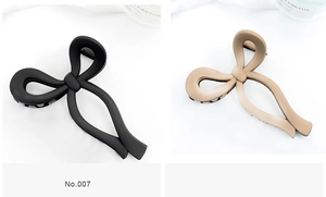 Detail view of two matte butterfly hair claws in black and beige with spring mechanism