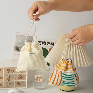 Close-up of portable corduroy and striped drawstring pouches held by a hand