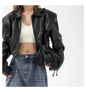 Detail of a punk style black triangular leather handbag with metallic buckle on a model