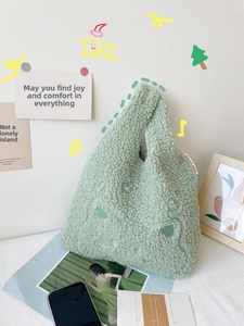 Detail of green plush wrist bag with cat embroidery and knotted handle design