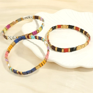 Detailed close-up of three Bohemian Tila bead bracelets with colorful enamel on a white shell plate