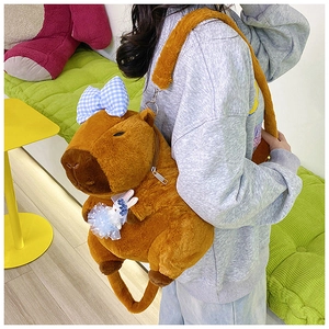 Brown capybara plush backpack with cute blue bow and rabbit doll worn by a model