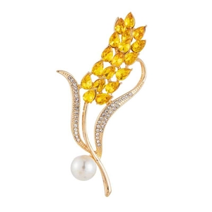 Detail of golden wheat brooch featuring yellow teardrop gems and white pearl accent
