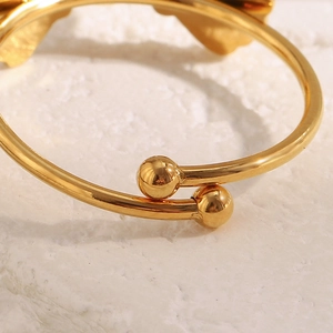 Détail macro du bracelet jonc doré ajustable avec boules sur fond de marbre