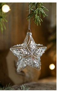 Macro shot of star-shaped clear glass ornament with silver sequins on Christmas tree
