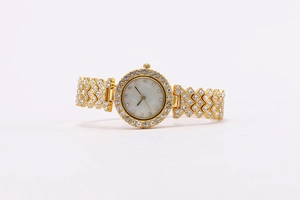 Macro shot of gold women's watch with crystal-encrusted bezel and mother-of-pearl dial