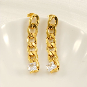 Detail of gold Cuban chain earrings featuring square clear zircon on a ceramic plate