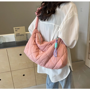 Lifestyle shot of large pink quilted tote bag worn by a model in a minimalist room