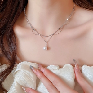 Gros plan d'un collier double épaisseur en argent avec un pendentif perle blanche