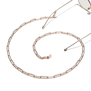 Golden paperclip chain glasses strap with silicone loops on minimalist white background