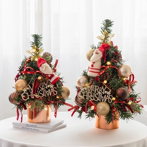 Mini Christmas trees with red ribbons and gold stars in rose gold pots on a table