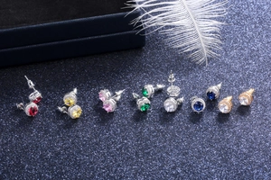 Macro view of round zircon stud earrings in various colors on a navy glitter surface