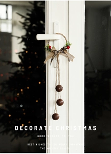Detail of Christmas wreath door hanger with plaid bow and rustic metal bells on door handle