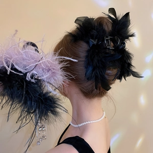 Detail of a fluffy feather hair claw clip with crystal bead tassels on a soft bun