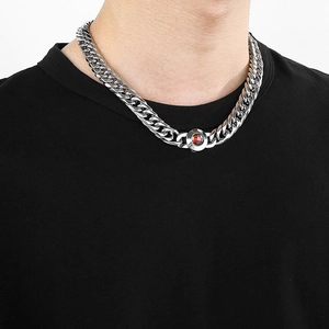 Détail d'un collier chaîne en acier argenté avec un pendentif rond en cristal rouge