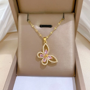 Macro detail of hollow butterfly pendant with pink gems and inlaid zircons on gold chain