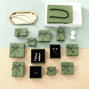 Flat lay of forest green jewelry gift boxes with ribbons and matching paper bags