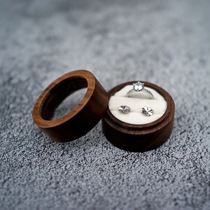 Macro shot of circular wooden wedding ring box with velvet lining and jewelry inside