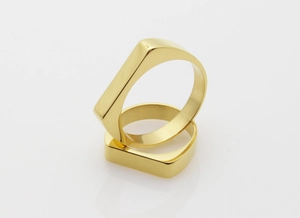 Detailed close-up of two polished gold geometric rings with flat square top design