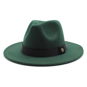 Detail of dark green wool fedora hat featuring black ribbon and golden metal M emblem