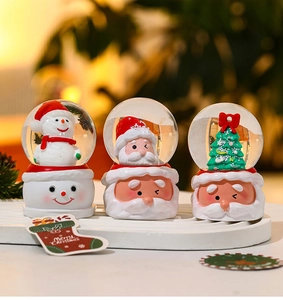 Detailed view of three Christmas snow globes with resin bases featuring Santa and snowman