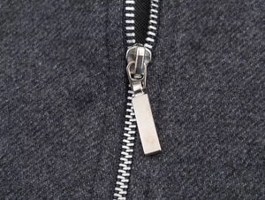 Detailed close-up of dark grey twill jacket featuring a silver metal zipper and fabric texture