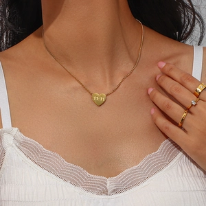 Detail of a gold heart pendant necklace engraved with 11:11 on a female model