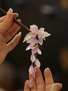 Detail einer hölzernen Haarnadel mit lila Harzblüten und goldenen Quasten