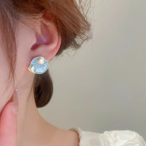 Detailed shot of blue enamel earrings featuring golden sun and heart relief patterns